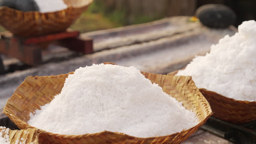 Farmer hands with natural bali sea salt, pure and coarse, hand harvested, woven bamboo basket, slow motion