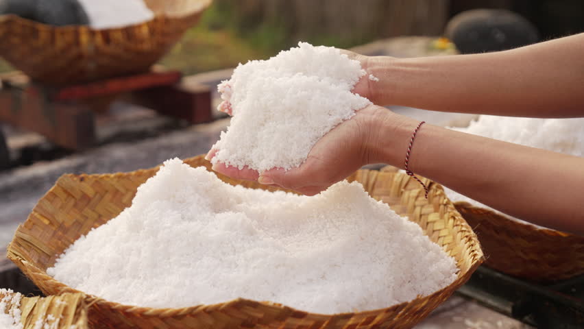 Farmer hands with natural bali sea salt, pure and coarse, hand harvested, woven bamboo basket, slow motion