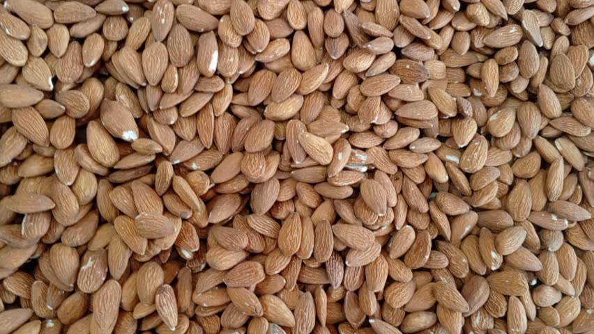 A close-up of a large pile of raw almonds showing smooth brown skins and natural texture; ideal for healthy food, grocery, culinary, and nut-themed visual projects with warm, organic tones.

