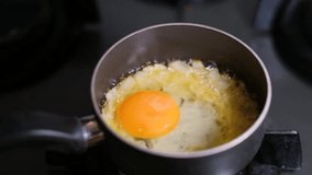 Slow motion egg cracking into frying pan with onions. Raw egg dropping into pan with caramelized onions in slow motion. Cooking egg and onions in skillet slow motion. - Powered by Shutterstock - Get 15% off with code: PIKWIZARD15