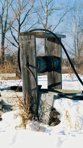 An old wooden well in the countryside in winter. Clean fresh water for general use. Vertical video, shorts.	