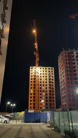 A captivating nighttime construction scene showcasing a crane and various buildings being built