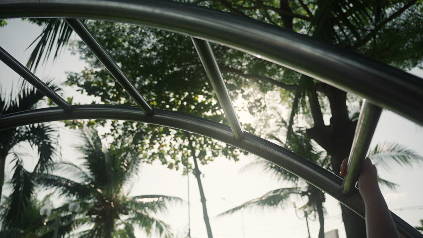 Child hand view sun shines through the trees onto a metal outdoor workout area. Close up Vertical Ladder for Outdoor Sport