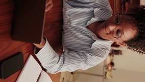 Vertical video,Focused young woman working from home on her laptop. She's wearing glasses and a striped shirt and looks thoughtful while working. - Powered by Shutterstock - Get 15% off with code: PIKWIZARD15