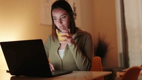 Young woman working from home, drinking orange juice and using laptop computer. Cozy evening atmosphere. - Powered by Shutterstock - Get 15% off with code: PIKWIZARD15