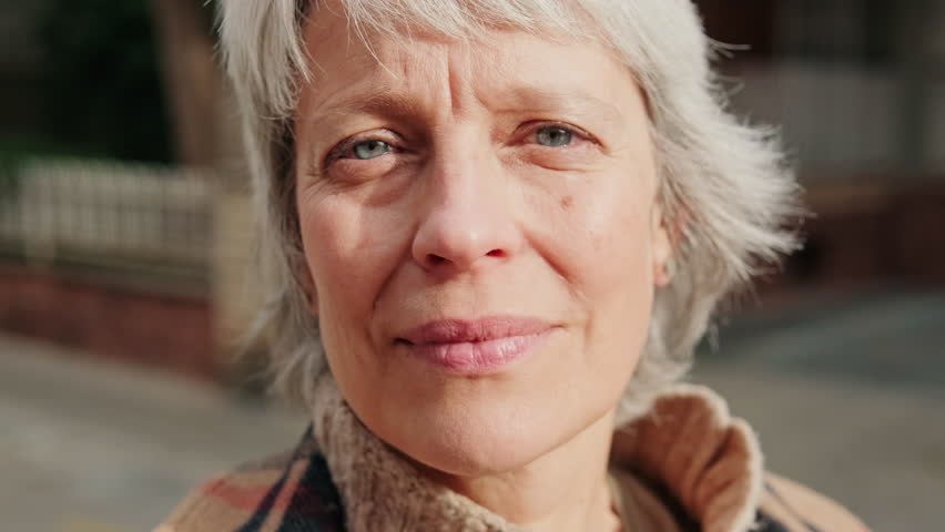 Portrait of a beautiful mature woman with grey hair looking at the camera with a hopeful look on her face. She represents confidence, wisdom, and kindness.