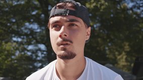Focused young man in white shirt and black cap practices tennis on a hardcourt, captured in a close-up shot, highlighting skill development and athletic training. - Powered by Shutterstock - Get 15% off with code: PIKWIZARD15