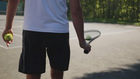Tennis player practices on hardcourt, holding racket and ball. Dressed in white shirt and black shorts, focused on training amidst lush greenery. - Powered by Shutterstock - Get 15% off with code: PIKWIZARD15