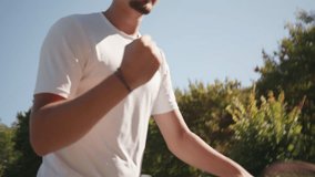 Whip pan of a young man in a white shirt and black cap practicing tennis on a hardcourt, surrounded by lush greenery. Dynamic motion highlights focused training, athleticism. - Powered by Shutterstock - Get 15% off with code: PIKWIZARD15