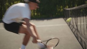 Close-up of a young man in a white shirt and black cap practicing tennis on a hardcourt, intensely focused on his swing. Lush greenery in the background indicates. - Powered by Shutterstock - Get 15% off with code: PIKWIZARD15
