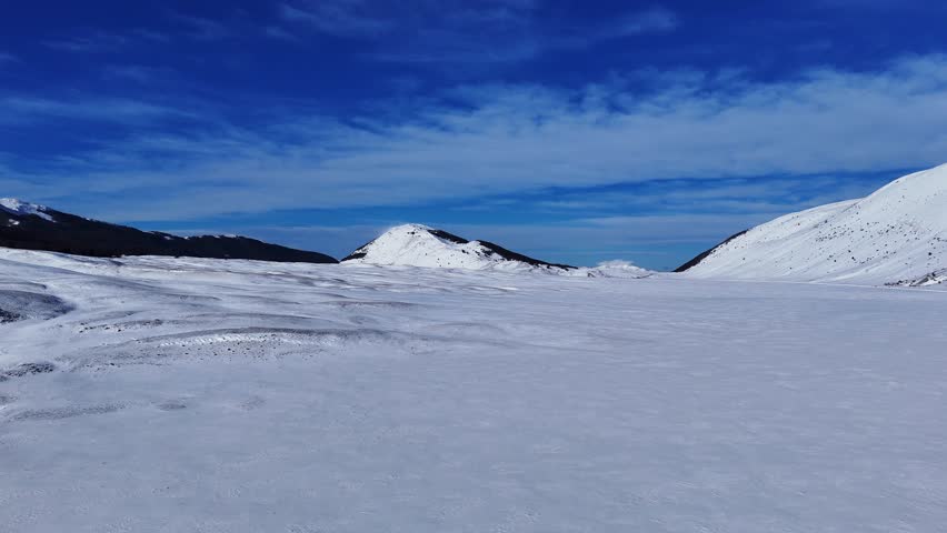 Drone aerial video flying over snowy plain towards mountains in Abruzzo, Italy