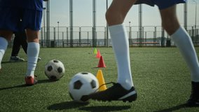 Close up of unrecognizable two football players practicing dribbling while coach watching - Powered by Shutterstock - Get 15% off with code: PIKWIZARD15