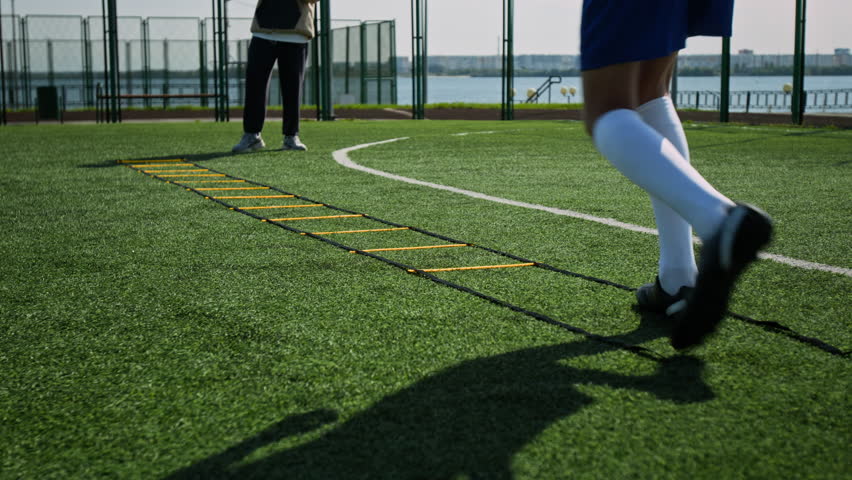 Slow motion of unrecognizable players using agility ladder to improve endurance and coordination