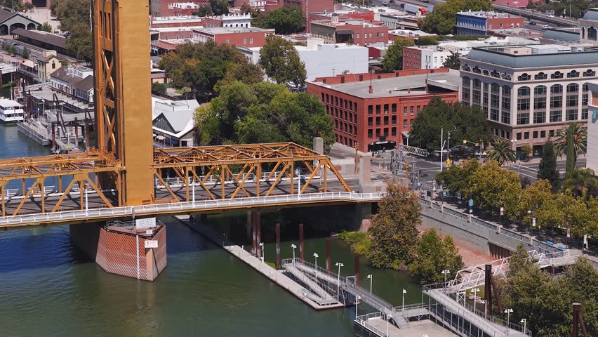 Aerial view of Sacramento, California, with the golden Tower Bridge, cityscape, highways, and a mix of historic and modern architecture.