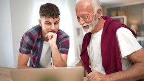 Senior grandfather helping teenage grandson with homework at a laptop, explaining lessons and sharing knowledge in a warm intergenerational tutoring moment at home - Powered by Shutterstock - Get 15% off with code: PIKWIZARD15