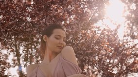 Caucasian woman in an off-shoulder pink dress gently closes eyes near sakura blossoms. Ideal for skincare ads, fashion promos, or nature-themed lifestyle videos. - Powered by Shutterstock - Get 15% off with code: PIKWIZARD15