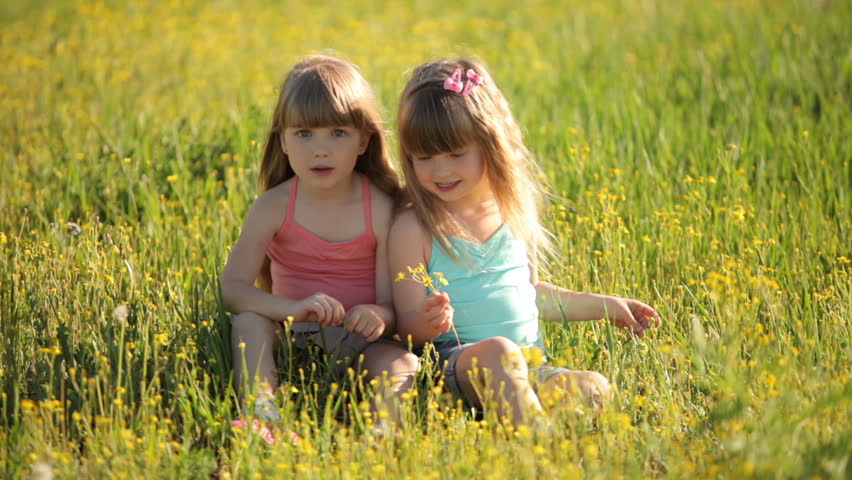 Cute kids sitting on grass and laughing
