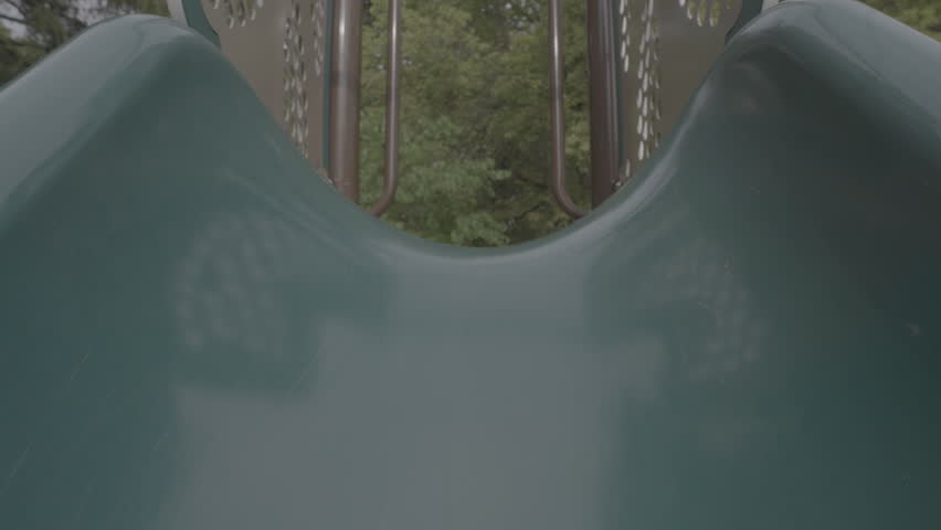 Symbolic slow motion pull-out shot of an empty playground slide. Perfect for themes of absence, nostalgia, loneliness, or urban childhood environments. S-Log3 Raw Format.