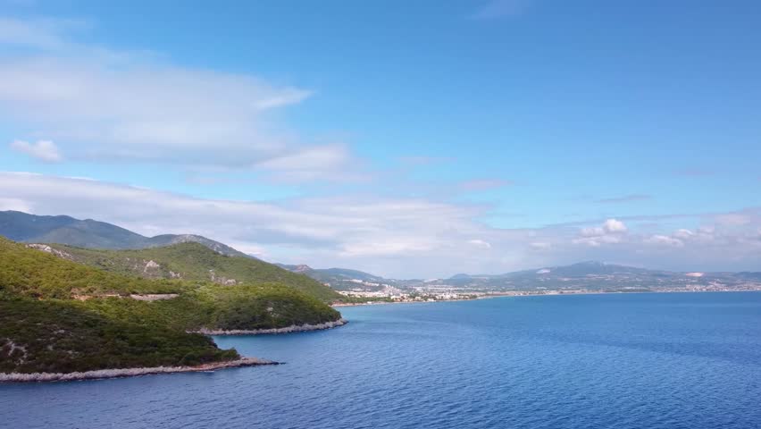 aerial footage showcasing the coastal landscape of Dilek Peninsula Buyuk Menderes Delta National Park in Turkey. Featuring lush green mountains meeting the clear turquoise waters of the Aegean Sea, wi