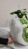 Florist ties a ribbon bow on a finished white and green bouquet - Powered by Shutterstock - Get 15% off with code: PIKWIZARD15