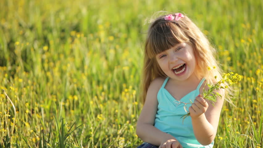 Little girl sitting in  field with bunch of flowers
