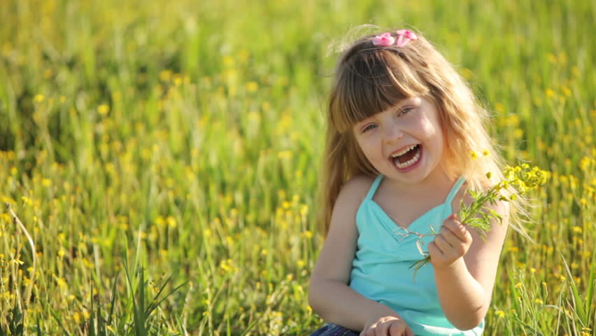 Little girl sitting in  field with bunch of flowers
