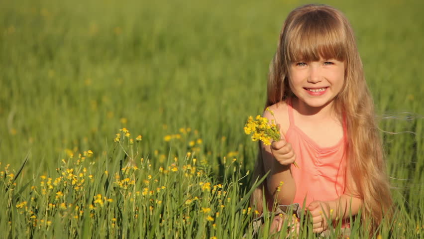 Cute child sitting on grass with flowers
