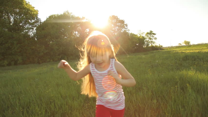 Pretty girl running on grass and smiling with flare 