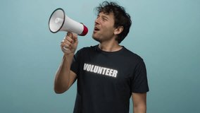 Hispanic man with megaphone passionately cheering in volunteer shirt against blue background - Powered by Shutterstock - Get 15% off with code: PIKWIZARD15