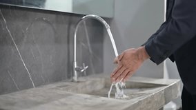 Businessman washes his hands thoroughly with water in a modern bathroom - Powered by Shutterstock - Get 15% off with code: PIKWIZARD15