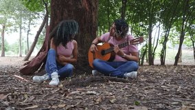 hispanic couple playing guitar sitting in a park, romantic young lovers dating together relaxing with music, boyfriend seducing girfriend singing - Powered by Shutterstock - Get 15% off with code: PIKWIZARD15