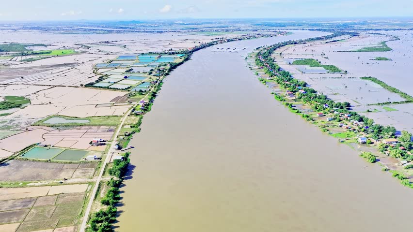 Aerial view of the Mekong River during the flood season, with surrounding rice fields, villages, and farmlands submerged under water in the Mekong Delta, Cambodia