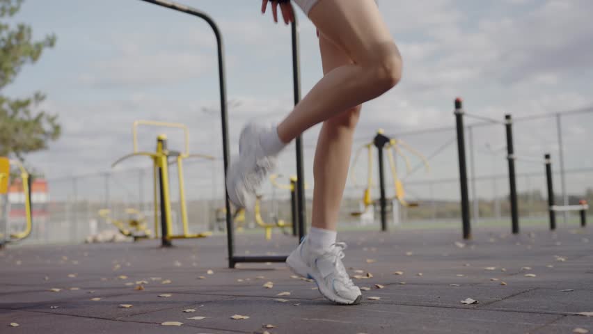 A focused young woman wearing modern sportswear, pausing her outdoor workout, gazes confidently at the sky. Woman in Active Wear Taking a Break During Outdoor Workout - Powered by Shutterstock - Get 15% off with code: PIKWIZARD15