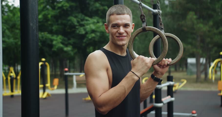 Handsome sporty guy prepare exercising with gymnastic rings. Man building arm muscles with exercise. Fitness Sportive fit man doing fitness exercises on sports rings. gymnastic rings.
