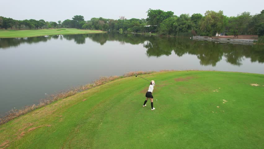 Drone view of professional female golfer playing on scenic golf course. Attractive beautiful woman enjoy outdoor recreation with light exercise and sport lifestyle while playing golf at course ground.