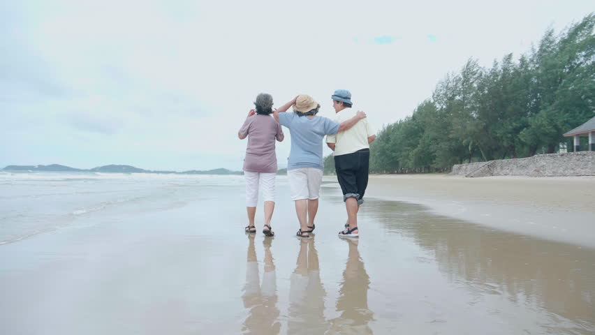 Group senior asian woman laughing and playing together at beach, enjoy vacation with friendship after retirement, cheerful elderly group with fun, relaxation with happiness and carefree in summer.