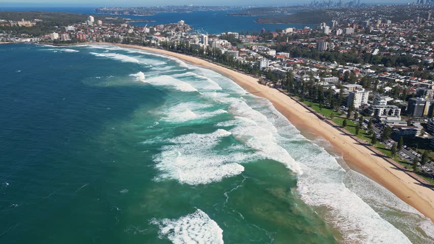 Sydney, Australia : Tilt up and forward footage of the long Manly sandy beach and its seaside resort area. Located in northern Sydney, New South Wales, Australia