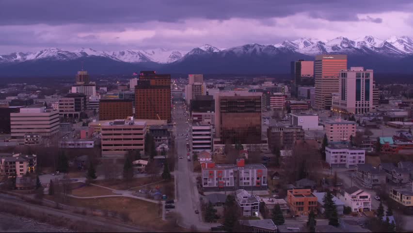 This video showcases a stunning view of the Anchorage, Alaska, city skyline set against the majestic backdrop of the snow-capped Chugach Mountains