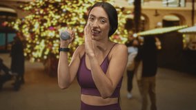 Woman holding dumbbell and wiping her face in building decorated with christmas lights and tree; holiday fitness determination. - Powered by Shutterstock - Get 15% off with code: PIKWIZARD15