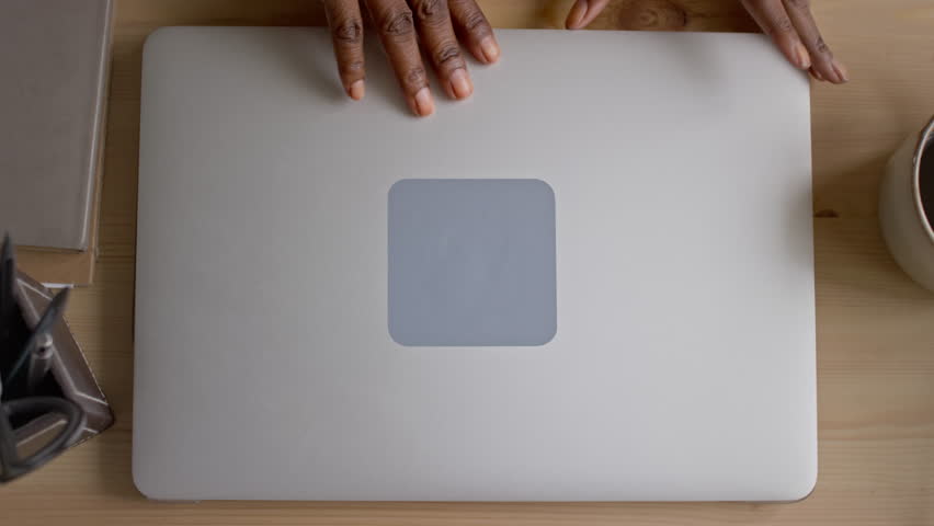 Top view close-up of hands of anonymous black woman opening laptop cover and pressing power button, while switching on computer to browse internet for entertainment or work