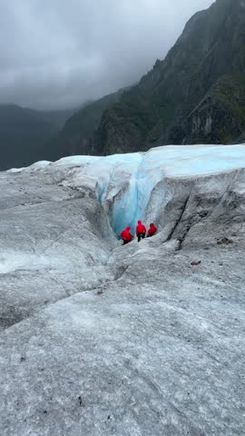 Tourists of queen Elizabeth cruise explore a deep blue crevasse on a glacier surrounded by misty mountains near Juneau, Alaska, USA, September 11, 2025. The scene captures the raw beauty of Alaska 