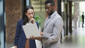 Tech colleagues scrolling laptop, flipping binder pages and generating icon overlay before walking. Technology, teamwork, innovation, collaboration, digital, modern, business - Powered by Shutterstock - Get 15% off with code: PIKWIZARD15