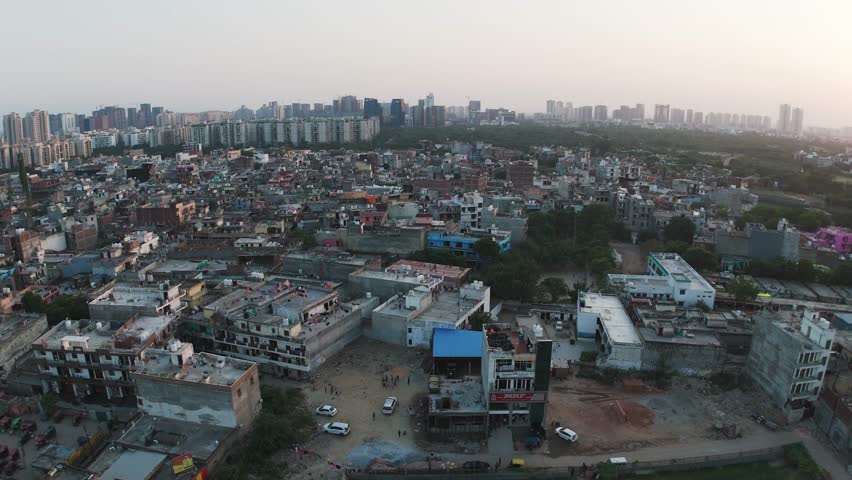The economic divide of a growing megacity. Drone footage reveals a low-income housing colony directly beside modern, wealthy apartment complexes and skyscrapers in India.
