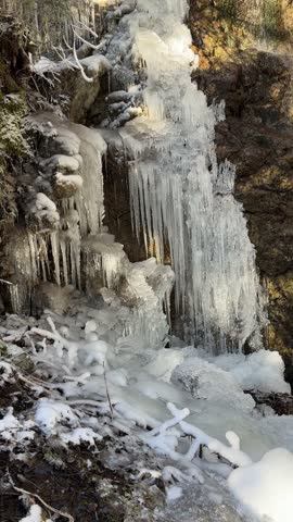 Close up view of a frozen waterfall with impressive icicles on a sunny winter day in the mountains