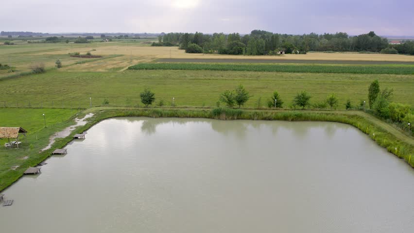 Beautiful rural landscape featuring a tranquil pond surrounded by lush greenery in the countryside