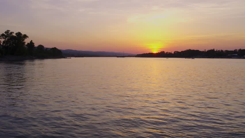 Serene sunset over calm waters along the riverbank at dusk