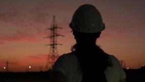 Silhouette of electrical engineer in hard hat walking towards power line tower and using tablet in evening at sunset - Powered by Shutterstock - Get 15% off with code: PIKWIZARD15