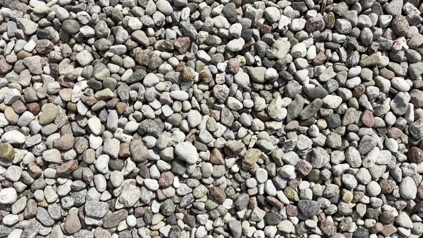 The camera falls on pebbles pattern. Colored rock stones, red granite and grey basalt pebbles textured background. Rounded gravel stones from different minerals