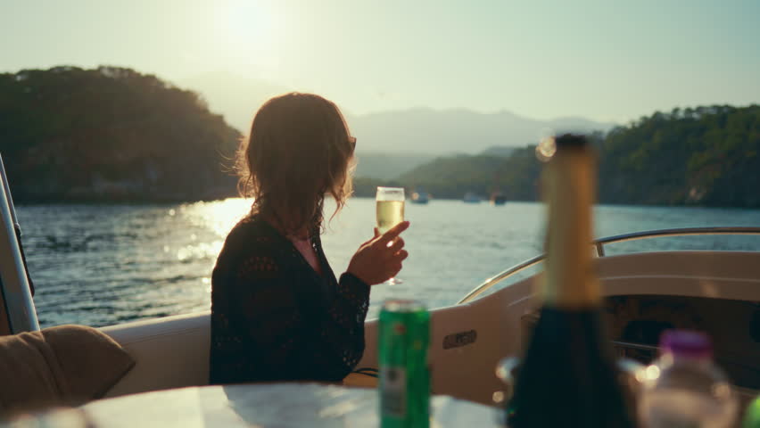 Woman enjoying luxury life, drinking champagne on board of yacht, travel by sea. Romantic dinner with sea view, summer vacation and holidays, relax time for recovery life energy, rich lady traveling