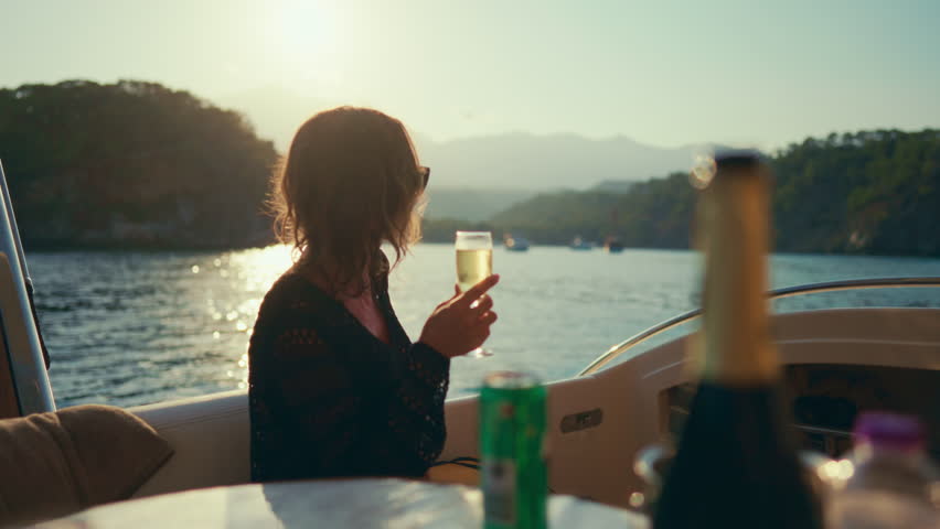 Woman enjoying luxury life, drinking champagne on board of yacht, travel by sea. Romantic dinner with sea view, summer vacation and holidays, relax time for recovery life energy, rich lady traveling